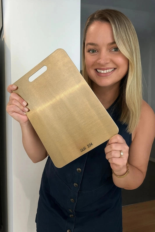 Woman holding a gold cutting board with 'SUIS 304' engraving.
